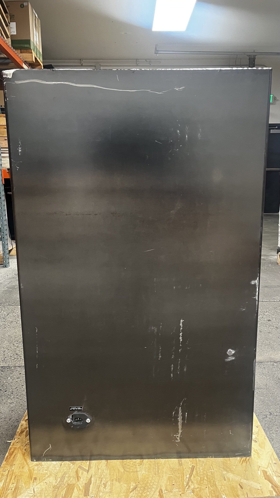 View of the back of the safe, it has scratches throughout the back. It also has a power outlet on the back. 