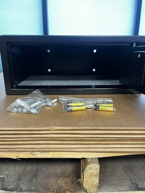 View of the inside of the safe, it comes with the bolt down screws. It also, has two override keys and the batteries needed to power the lock. 