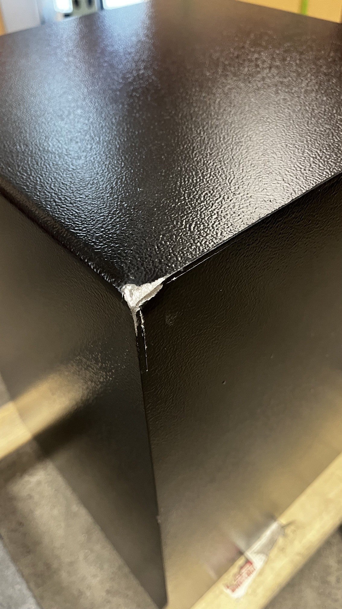 View of a big chip on the paint on the top back corner of the safe. 