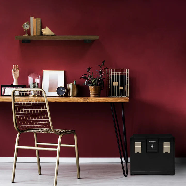Wooden desk with decorative items against a red wall, featuring a gold chair and Honeywell 1108 Safe
