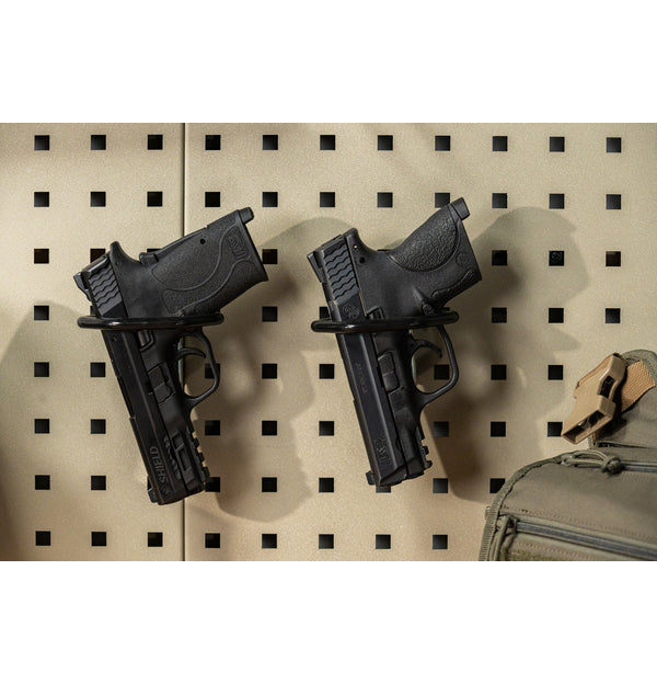 Two black pistols mounted on a Square-Lok Pistol Rack accessory attached to a tan pegboard panel
