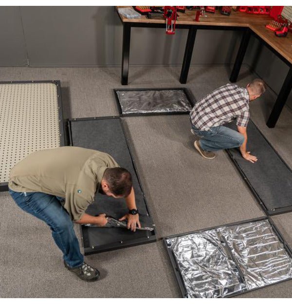 Two people assembling the modular panels of the Hornady VEXIS Mobilis safe on a workshop floor using power tools