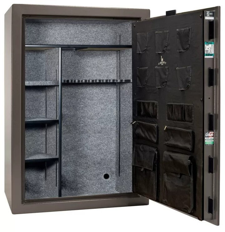 Liberty Safe 1776 50-Gun Safe with door open showing empty gray fabric interior, adjustable shelving, rifle racking with center divider, and Liberty-branded canvas door panel with pistol pockets and document storage