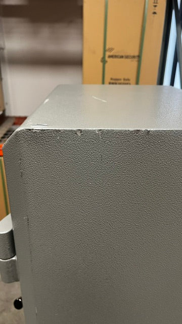 View of scratches and chips on the paint on the top of the safe. 