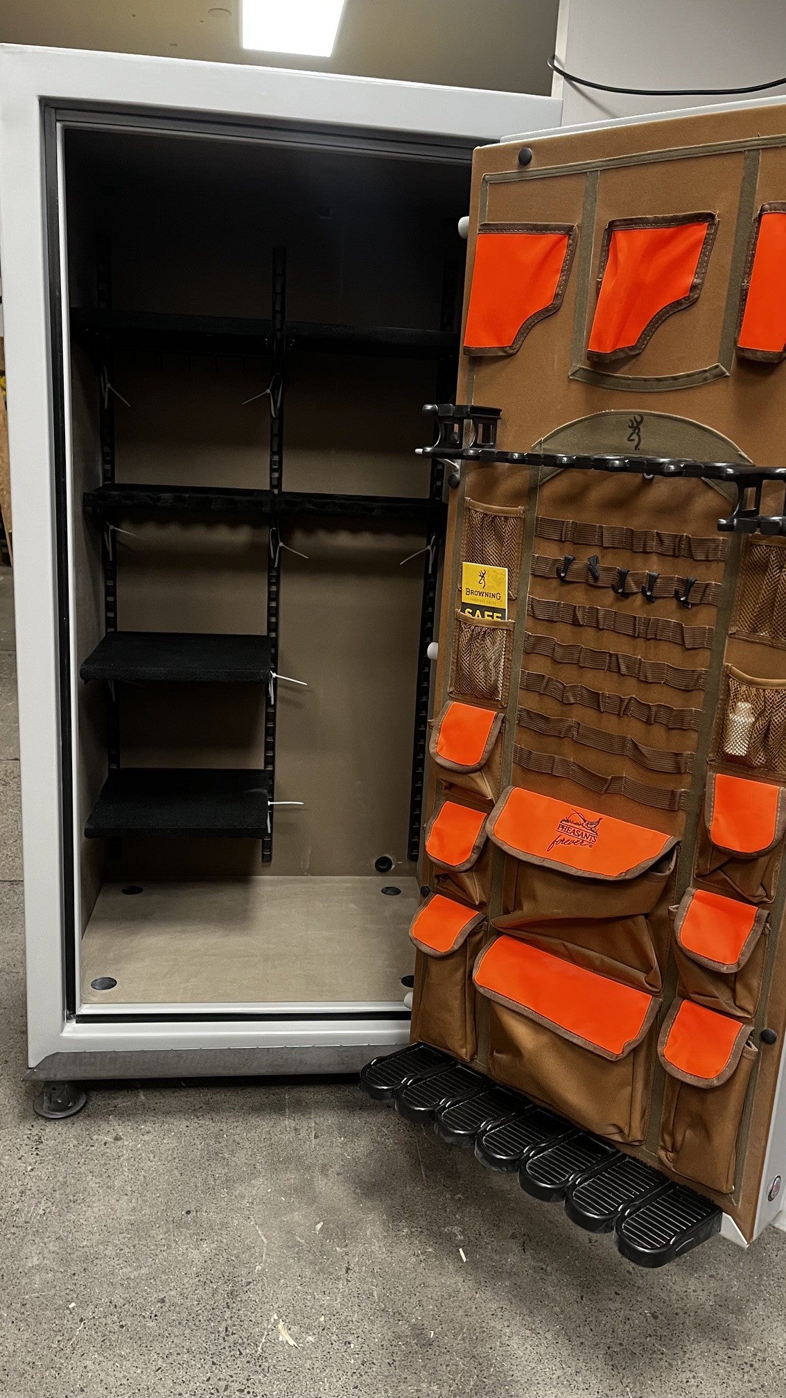 View of the safe with the door open. It comes with adjustable shelves and four predrilled holes to bolt down the safe. The door has room for three pistols and seven long firearms. 