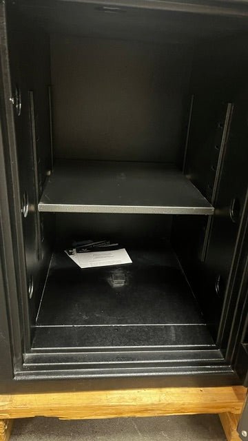 Close-up view of the inside of the safe. The safe has an adjustable shelf and a bolt down hole in the center of the safe. 