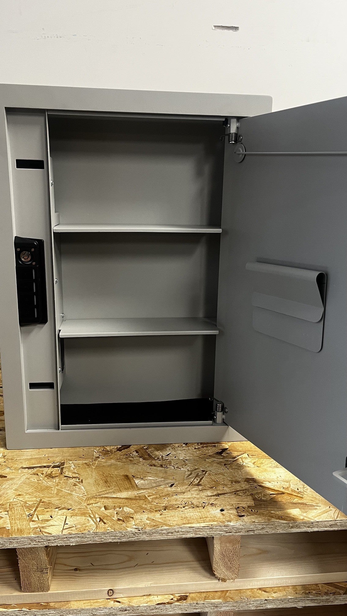 View of the inside of the safe. It comes with two shelves that are removable. It also has a magnet clip board to clip papers onto. 