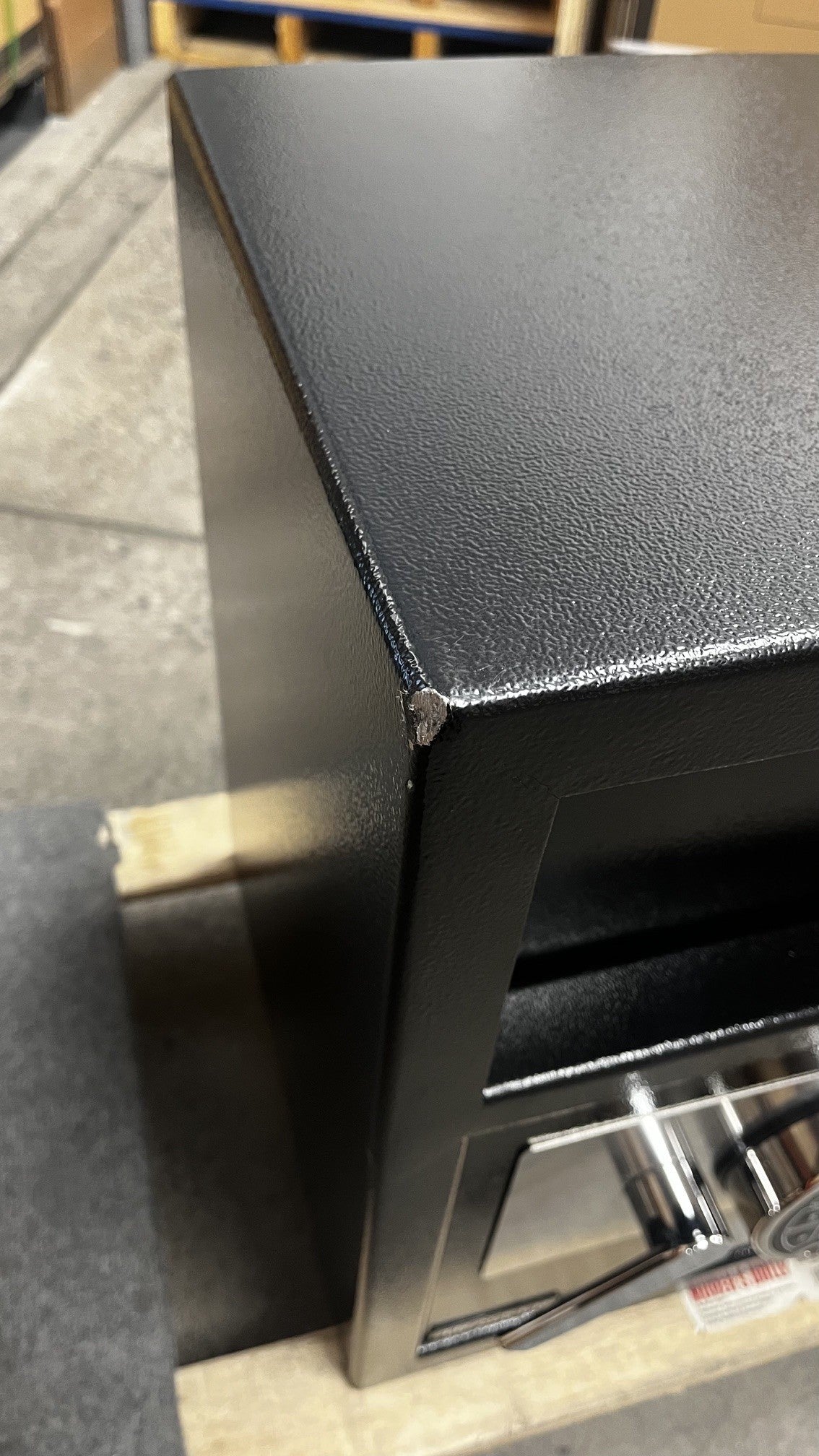 View of the dent and chip on the front of the safe. The damage is located on the top left corner. 
