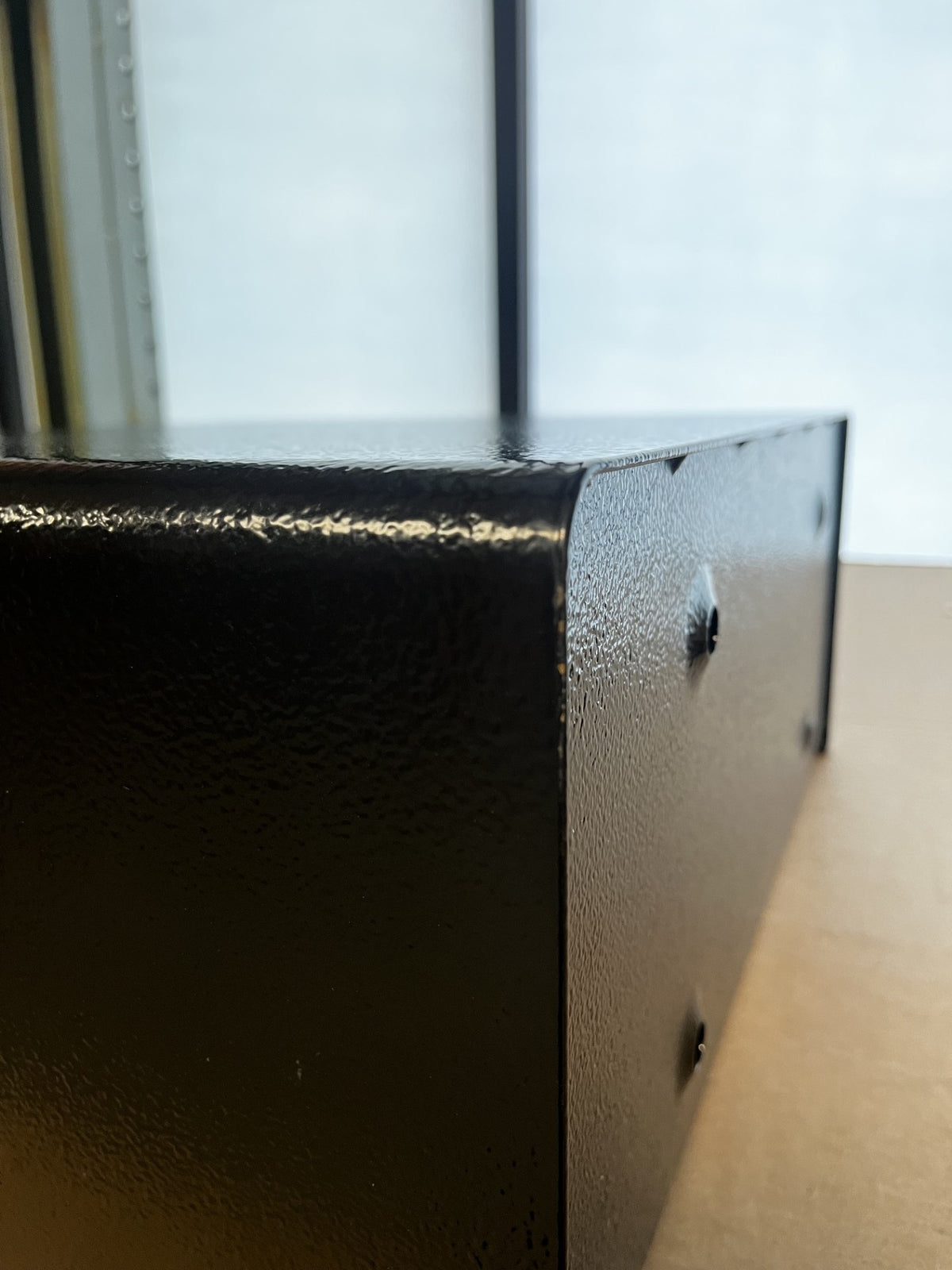View of the top right corner on the left side of the safe. It has small chips on the paint. 