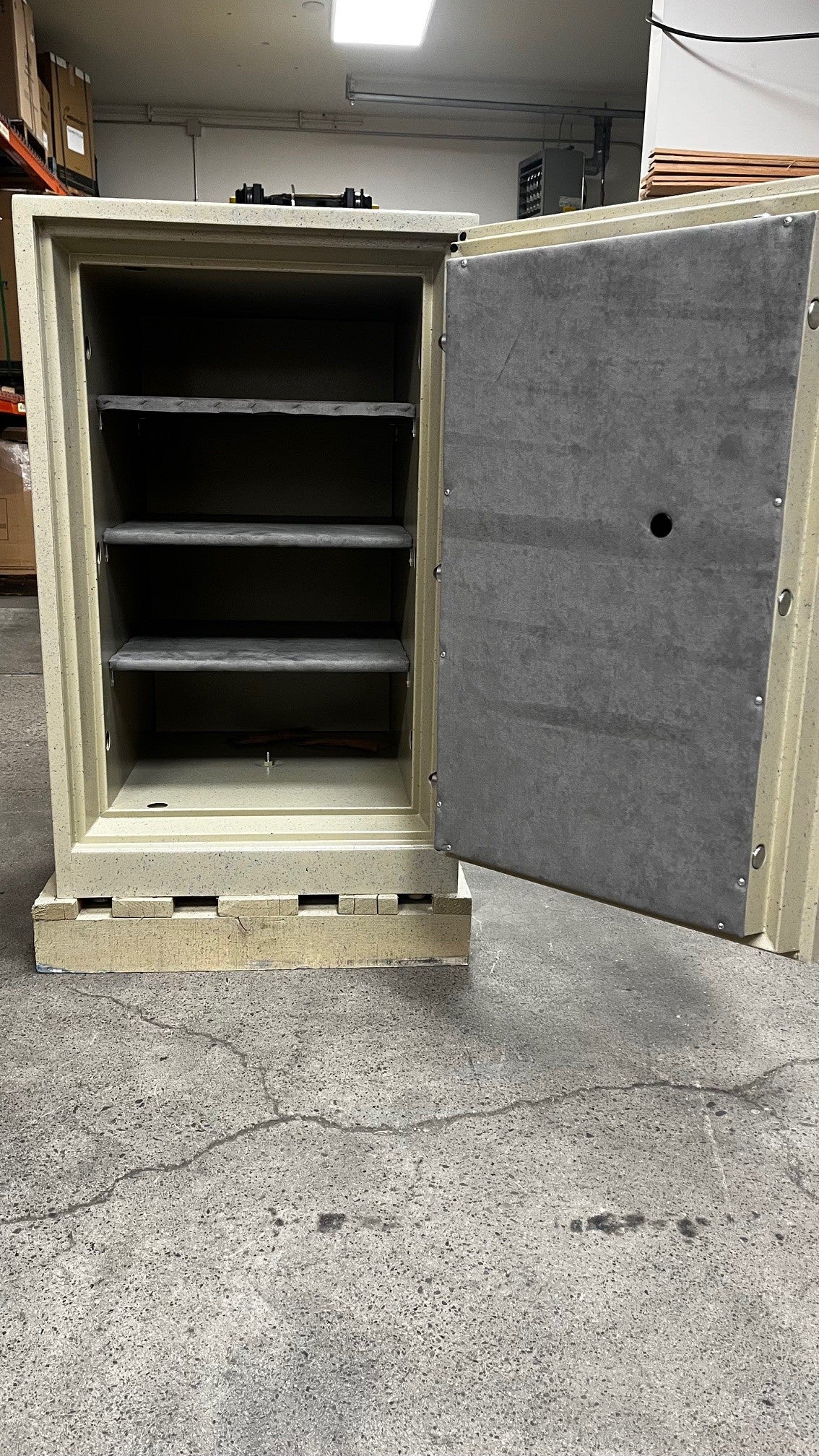 View of the safe with the front door open, it has three adjustable shelves and one center bolt down hole. 