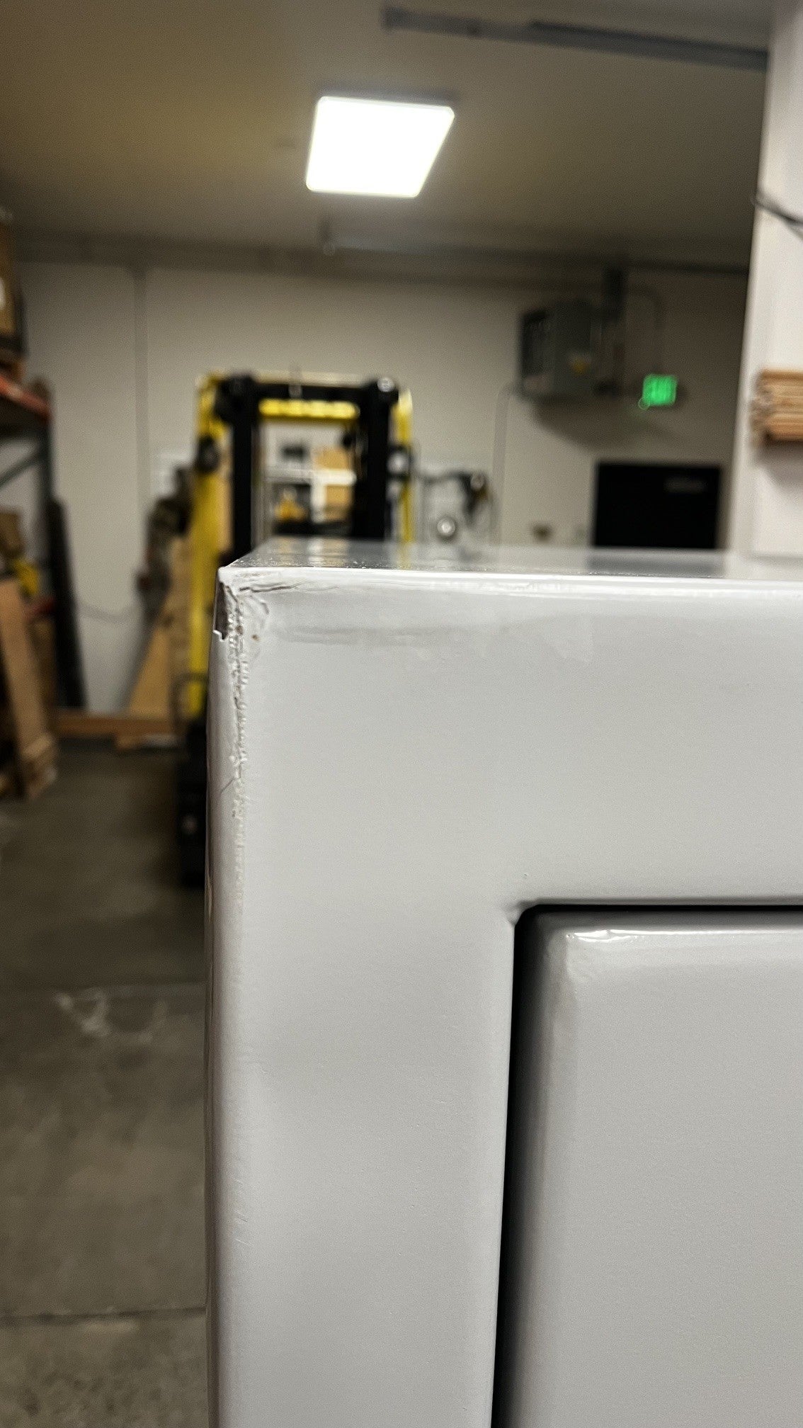 Close up of the top left corner. It has a dent and chip on the paint. 