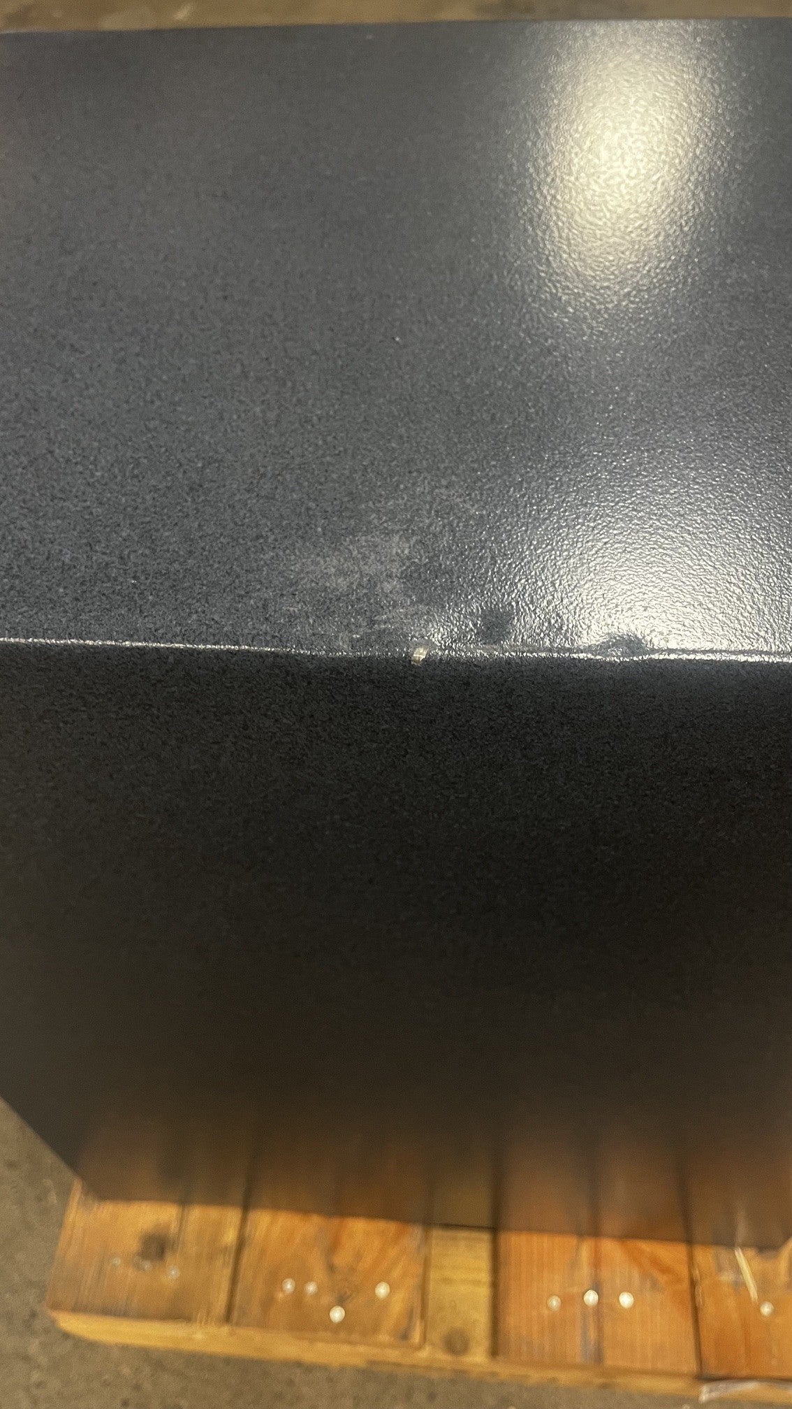 Top view of the left side of the safe. The top has a few dents and a chip on the paint. 
