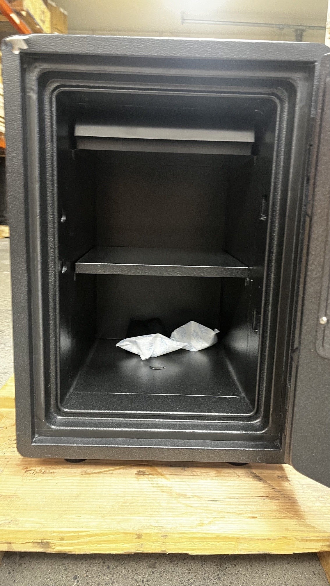 Close up view of the inside of the safe. The safe has one center bolt down hole, one adjustable shelf, and one removable tray on the top of the safe. 