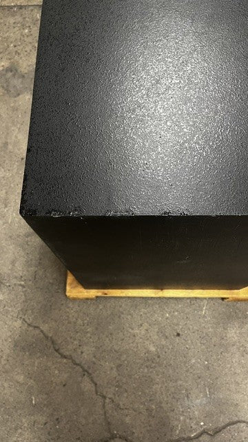 Another view of some paint chips on the top back of the safe. The paint chips have been painted in black to match the color of the safe. The chips are on the edge of the safe. 