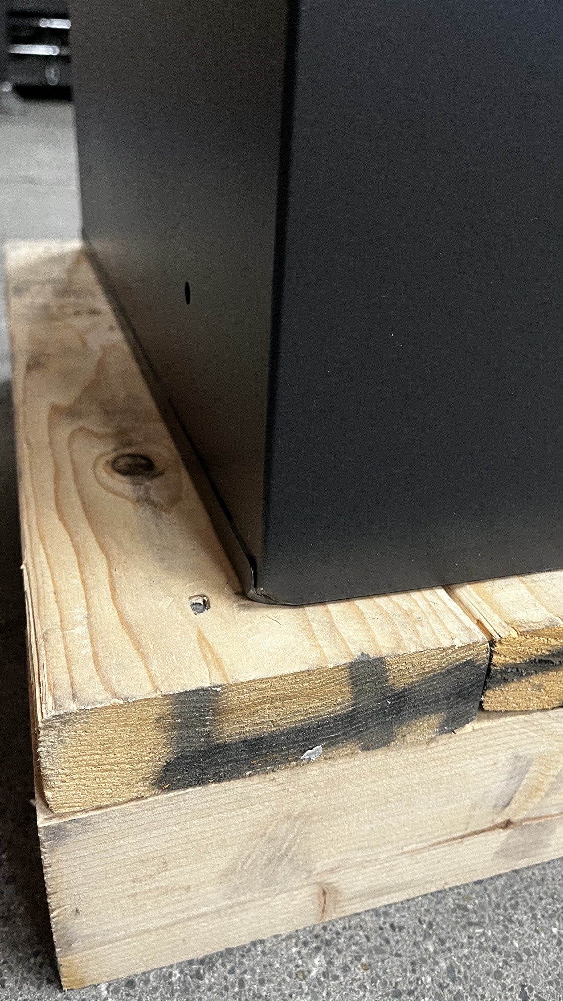 View of the bottom of the left corner on the left side of the safe. It has a dent on it. 