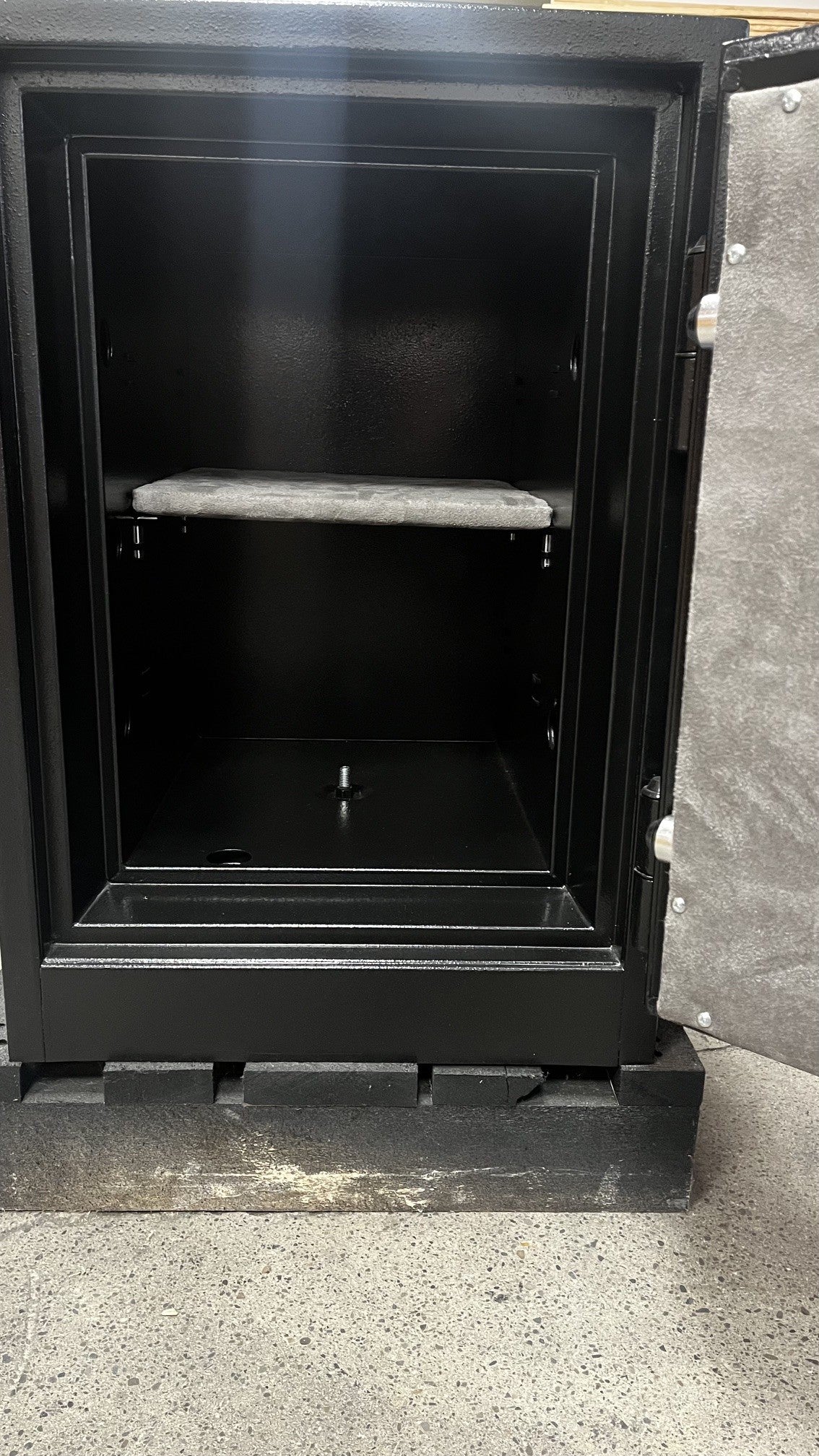 View of the inside of the safe. It comes with one adjustable shelf and a center bolt down hole. 