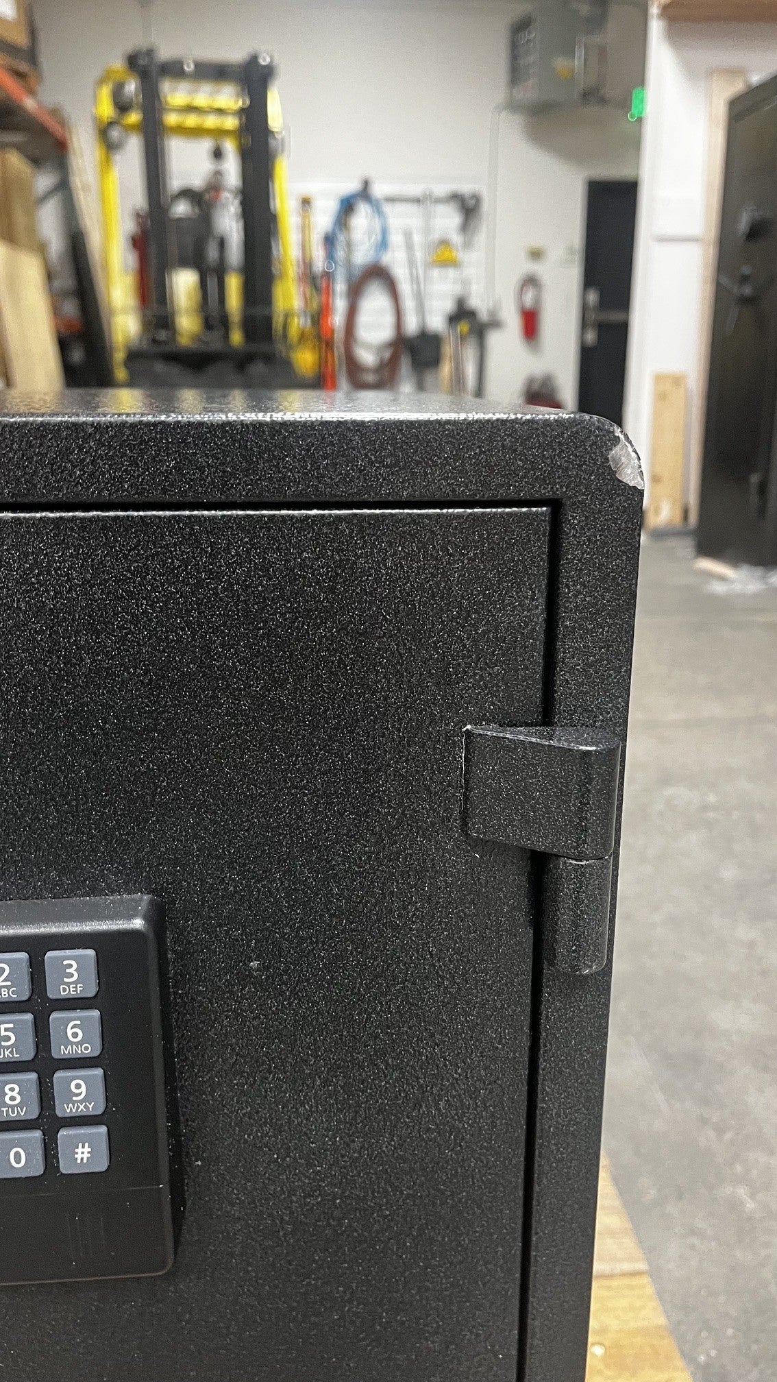 Close-up view of the front top right corner of the safe where it has a chip on the paint. 