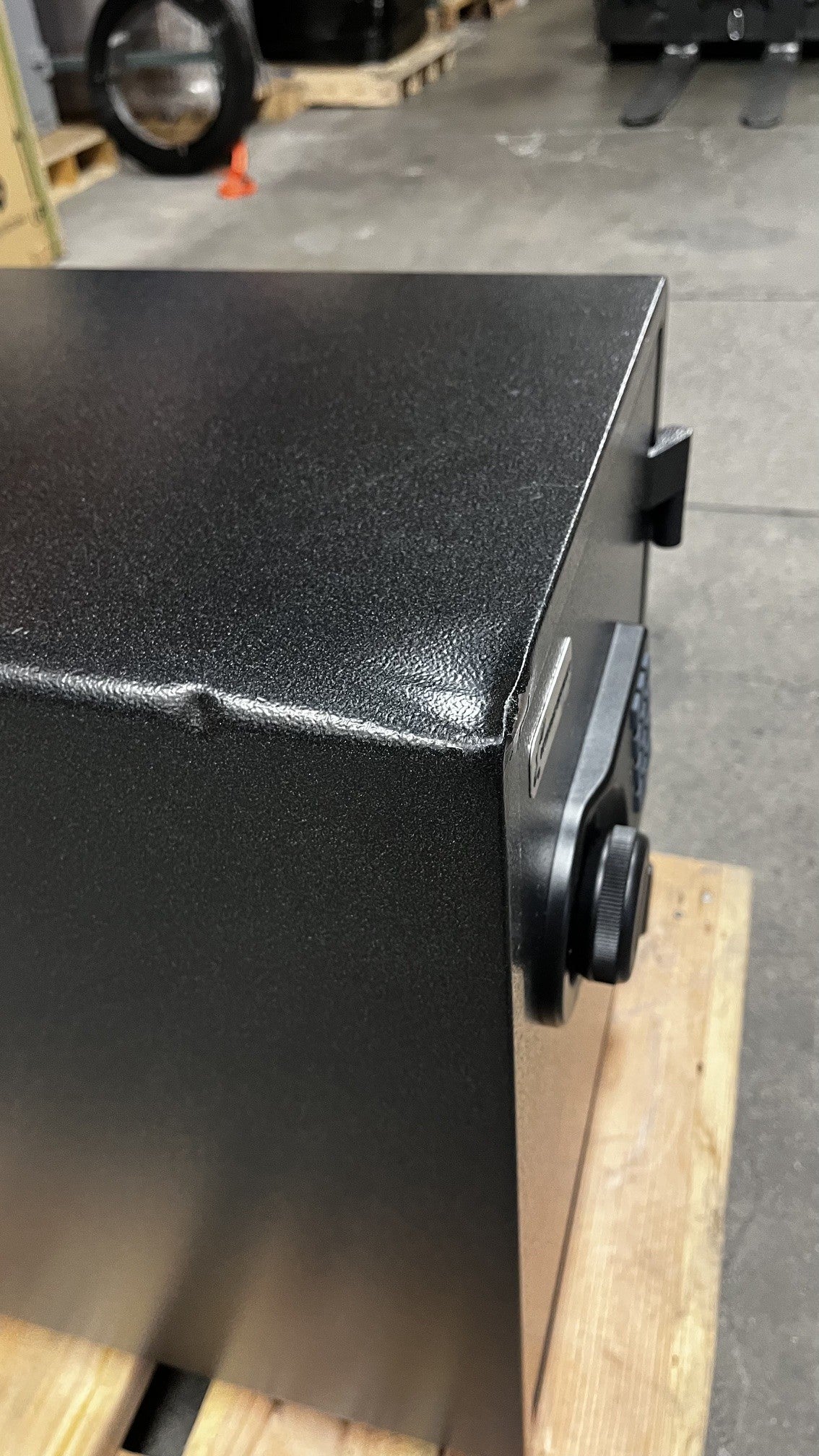 Top view of the safe, it has two dents on it. One is closer to the front of the safe. The other dent is alongside of the top left edge of the safe. 