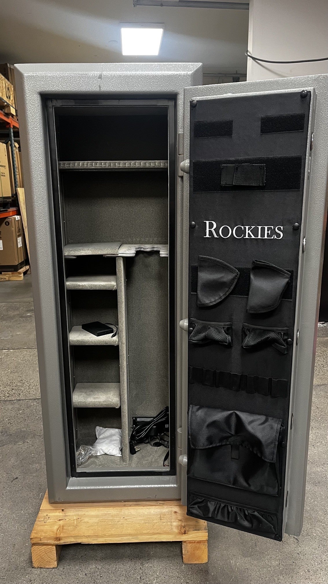 View of the safe with the door open, the door comes with the few handgun holders. It also has a document pouch. The inside comes with a few adjustable shelves and a power outlet to connect dehumidifier rods. The safe also has a light kit. 