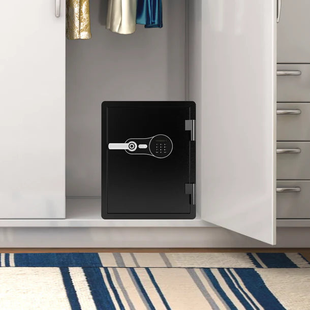 Barska AX14200 FV Pro 600 biometric fire resistant safe installed inside a home closet on the floor beneath hanging clothing, showing typical residential placement for home valuables and document storage