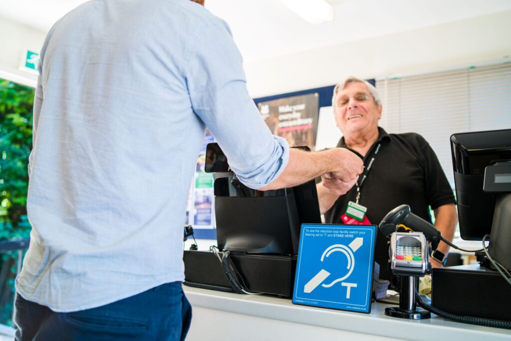 Contacta IL-AE97 installed at a retail service counter next to a payment terminal, with a customer at the register