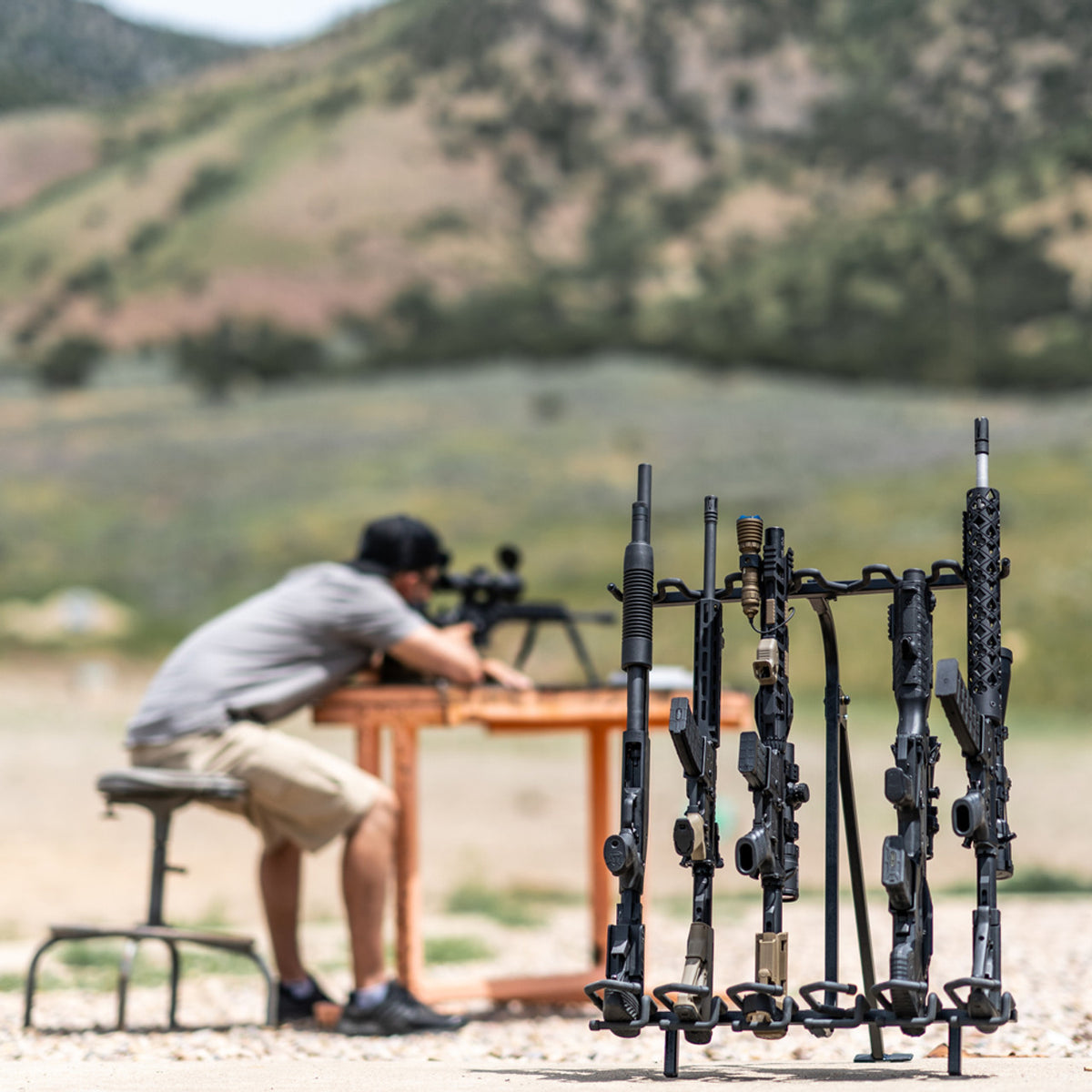 Man practicing shooting with rifles on a stand in an outdoor setting