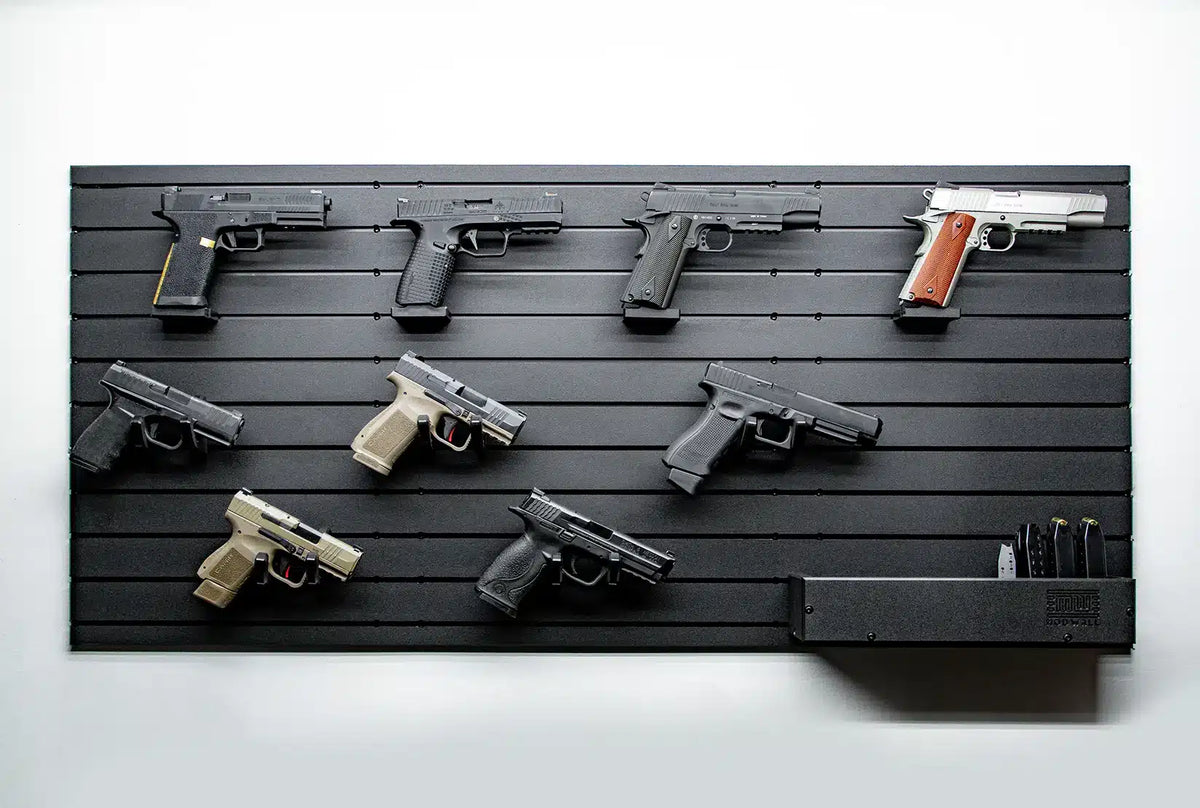 Display of various guns on a black slat wall against a white background