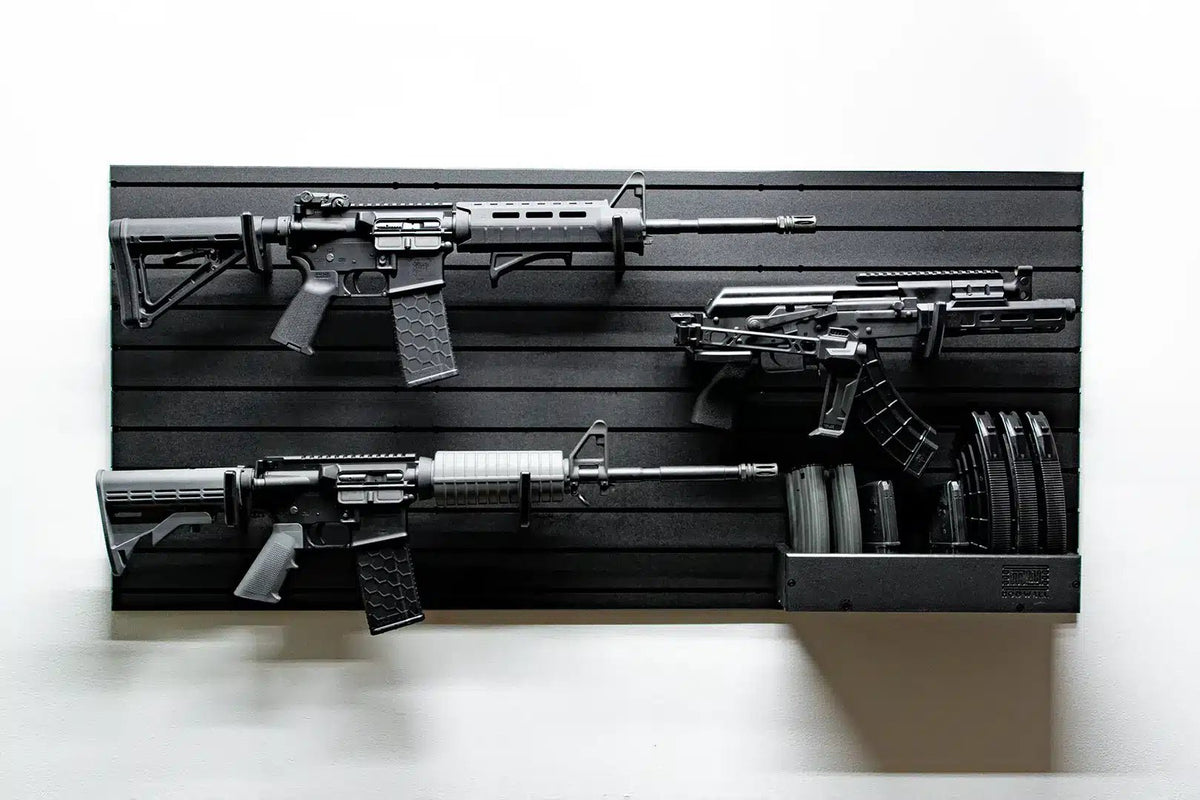 Three rifles displayed on a black slat wall against a white background