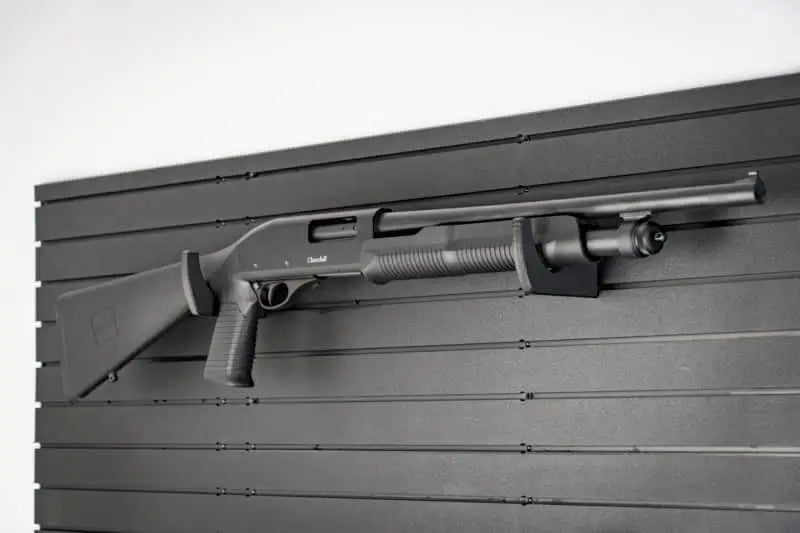 Black shotgun mounted on a gray slat wall