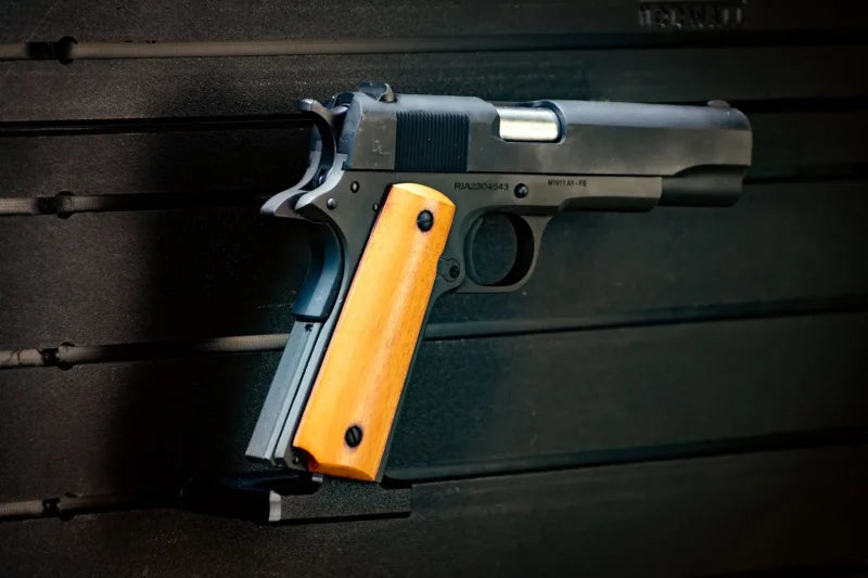 Handgun with yellow grip on a dark wooden surface