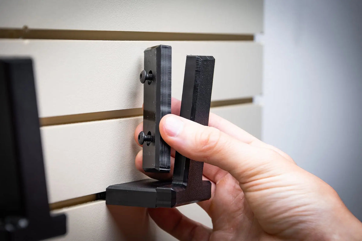 Hand holding a black metal tool against a neutral background
