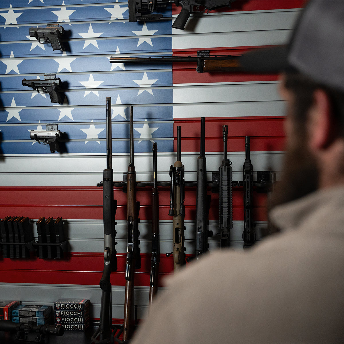 Man looking at firearms displayed against an American flag background
