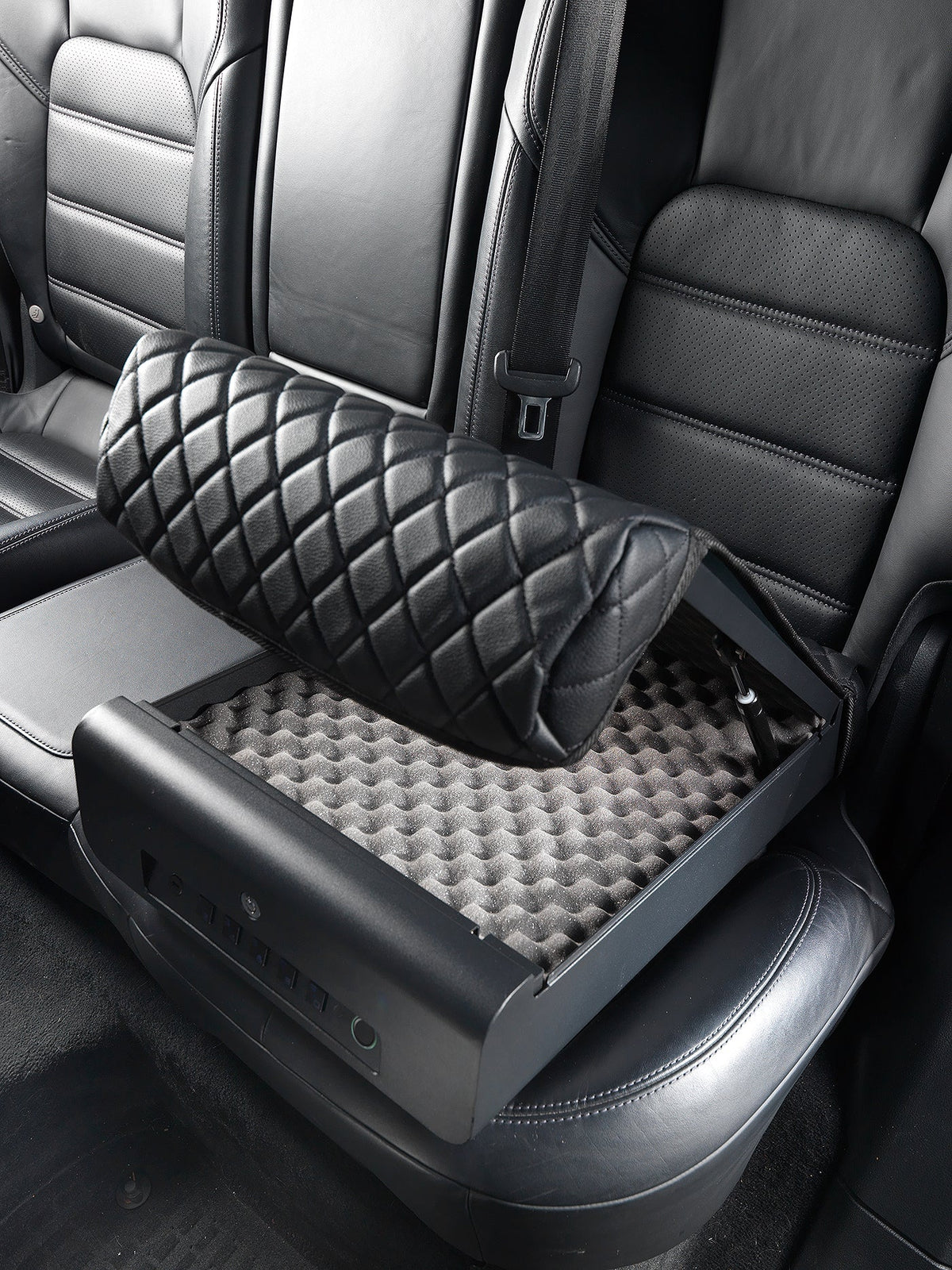 Car seat with a quilted black pillow and honeycomb pattern on a gray seat cover.