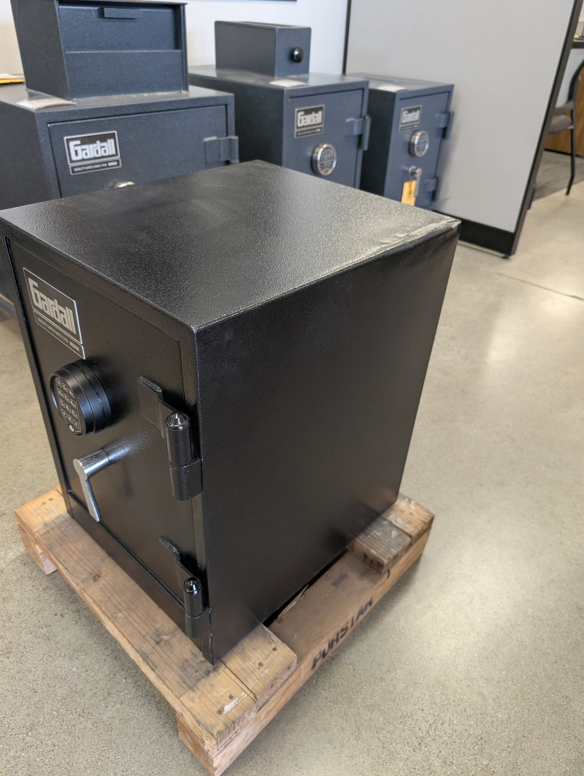 Side view of the front right side of the safe. On the back top corner, a dent is noticeable, and on the front top corner a chip on the paint is visible. 