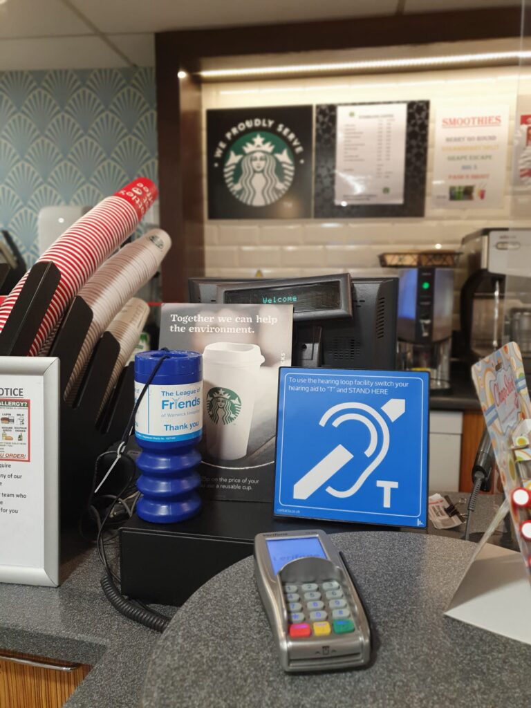Contacta IL-AE97 hearing loop aerial placed on a Starbucks coffee shop counter next to a card payment terminal