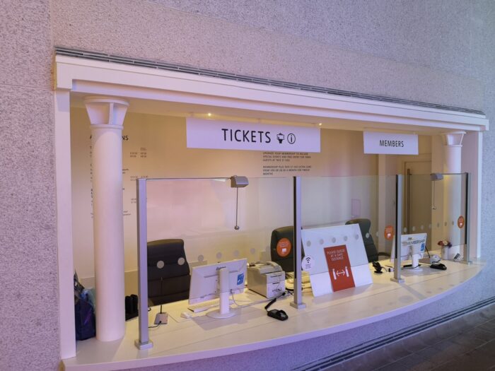 Contacta STS-K064 anti-vandal window intercom deployed across the ticket and members windows at Tate St Ives, with glass-mounted microphones on stems at each customer position and staff units with gooseneck microphones behind the glass barriers