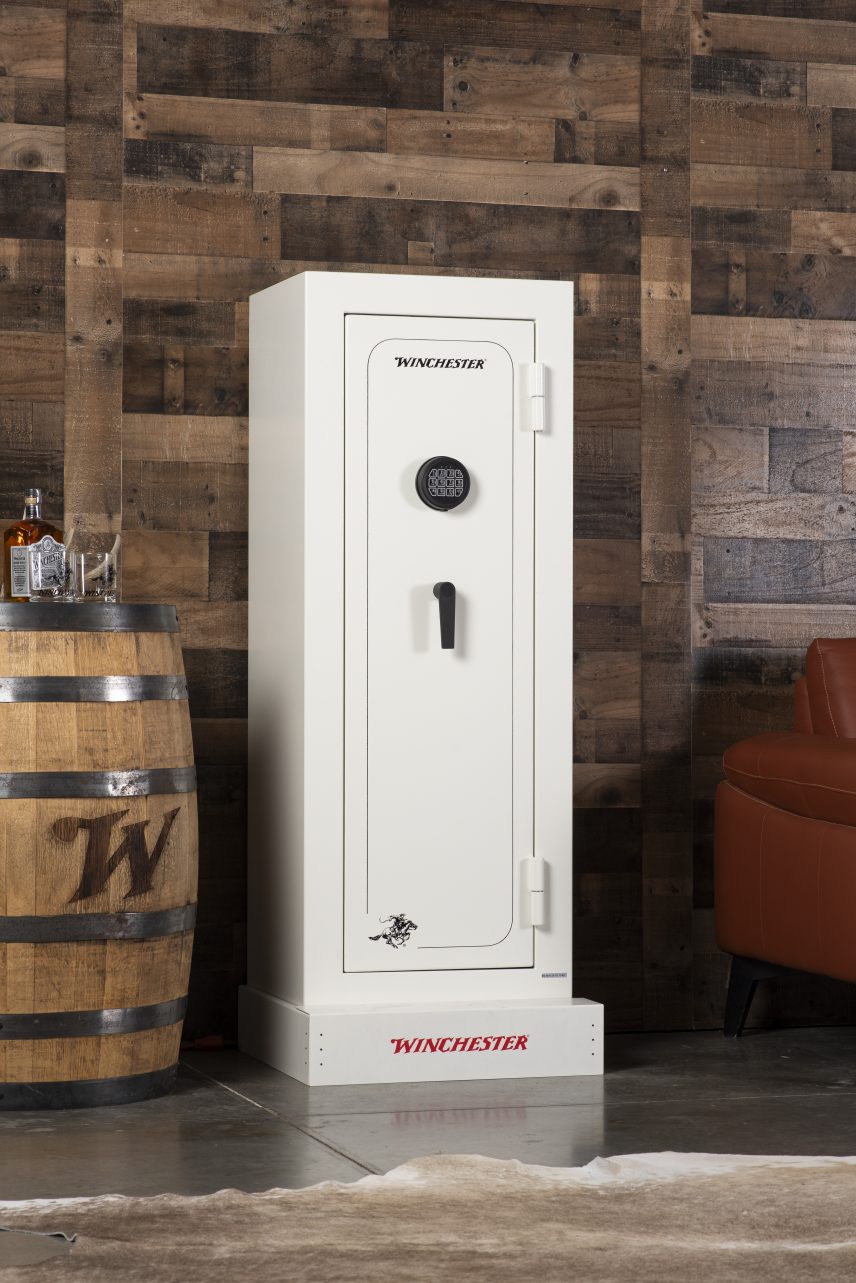 Winchester VaultLite 18 white gun cabinet in a reclaimed-wood den with Winchester barrel keg, leather chair, and cowhide rug