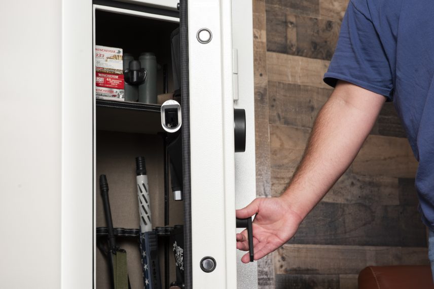 Winchester VaultLite 18 white gun cabinet being opened in a wood-paneled den showing loaded interior with Winchester ammo