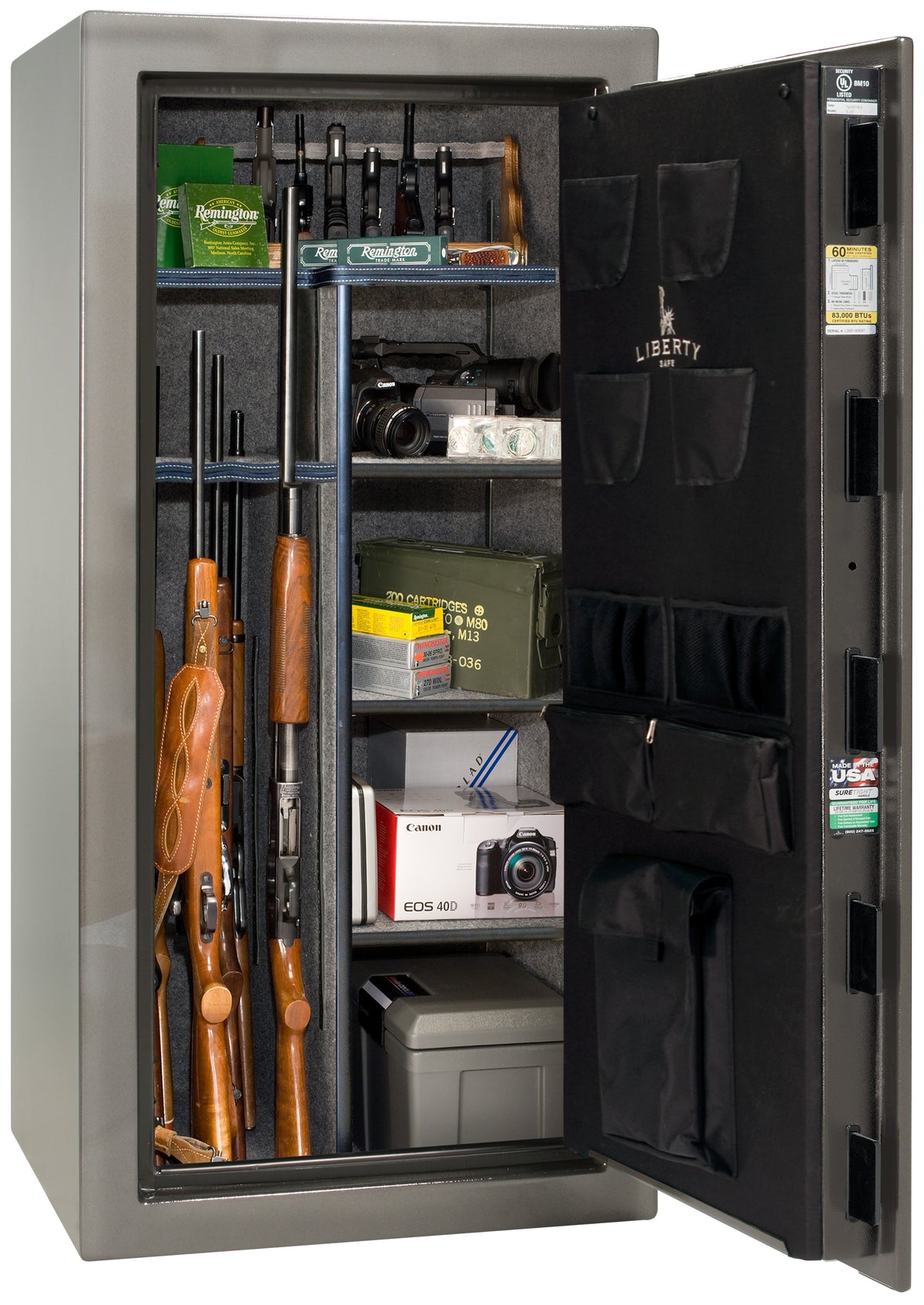Liberty Safe We The People 30 gun safe in gray with door open showing rifles in rack, Remington ammunition boxes, Canon camera, cash box, and valuables on shelves, with Liberty-branded canvas door panel storing pistols and documents