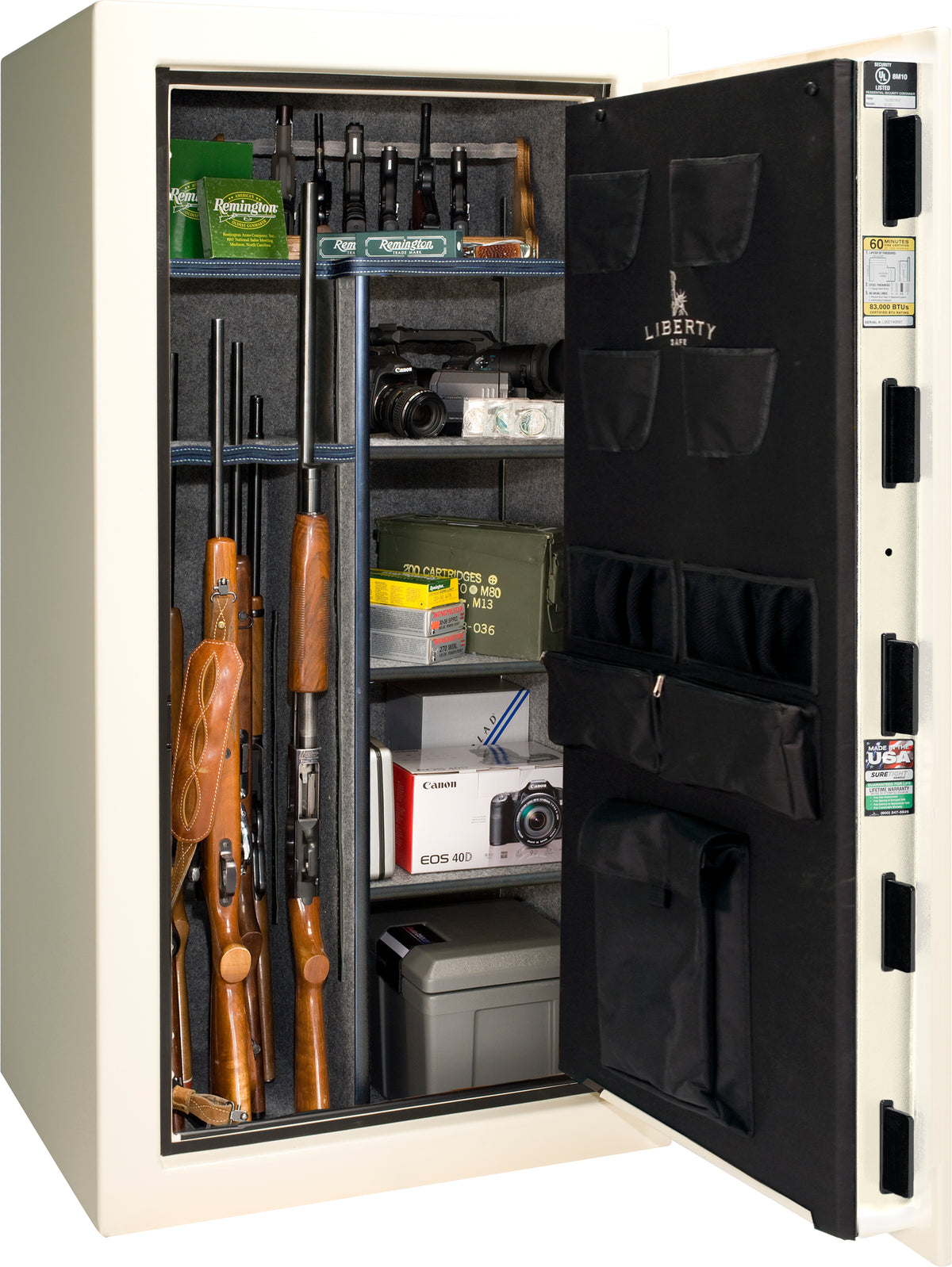 Liberty Safe We The People 30 gun safe in white with door open showing rifles in rack, Remington ammunition boxes, Canon camera, cash box, and valuables on shelves, with Liberty-branded canvas door panel storing pistols and documents