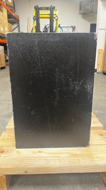 Back side view of the safe, the back has multiple scratches all around it. It has paint chips along the four edges. 