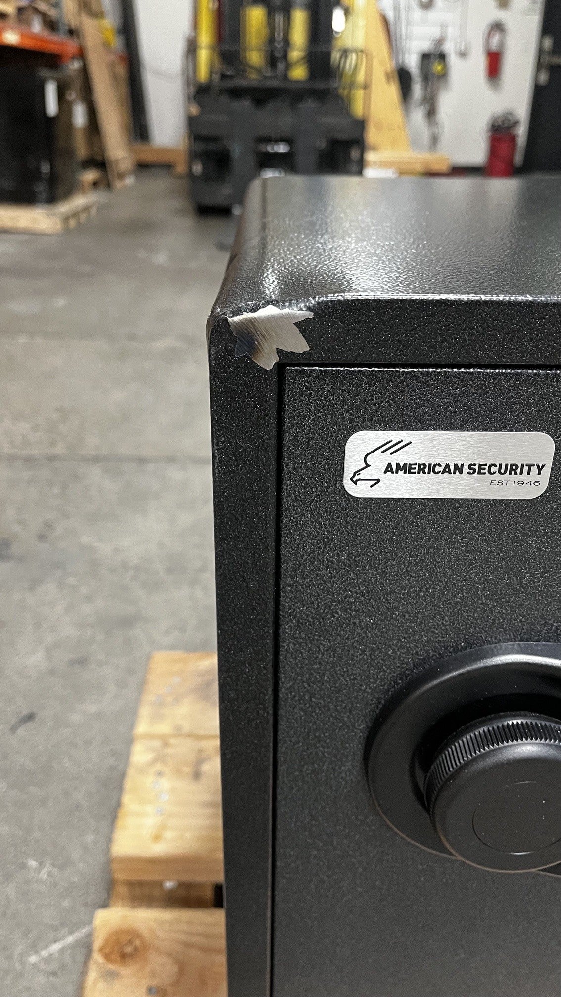 Close up view of the top left front corner where the paint is chip. The top of the safe has a dent on it as well. 