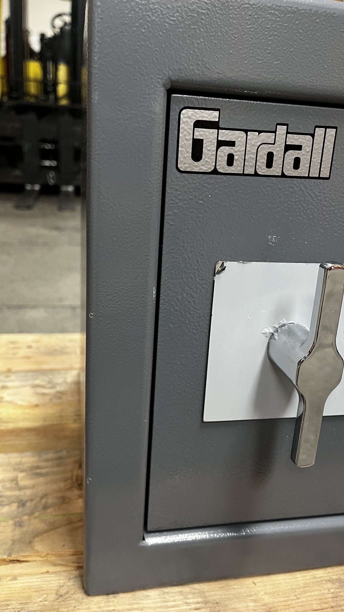 View of some small chips on the paint, alongside the edge of the safe. The white on the metal plate has peeled off a little on the top left corner. 
