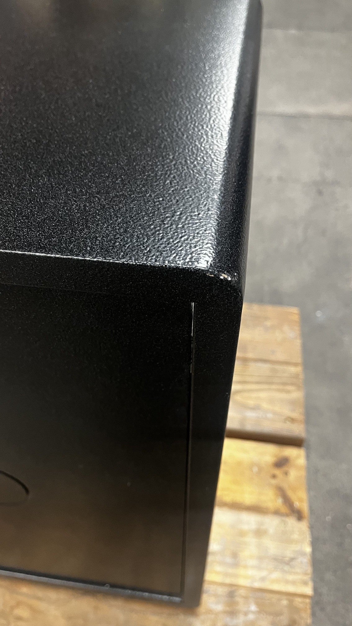 Close-up view of a small chip on the back top right corner of the safe. 