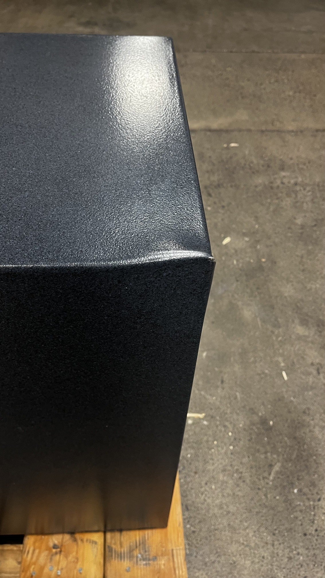Top view of back left corner. It has a dent on the corner and a small chip on the edge. 