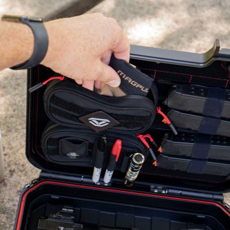 Hand detaching a Vaultek XE-RK zip pouch from the MOLLE lid panel to demonstrate the removable pouch feature
