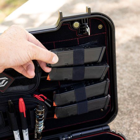 Hand pulling a pistol magazine from the Vaultek XE-RK elastic loop organizer holding four magazines on the LifePod XE lid