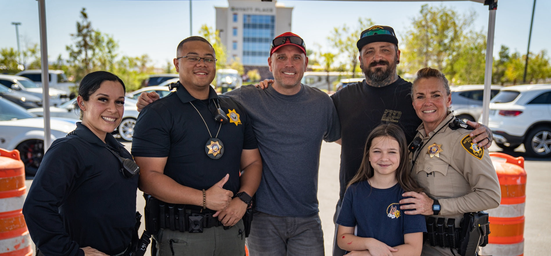 Law enforcement officers with a father and his children at a Project ChildSafe community event, supporting responsible firearm storage and safety
