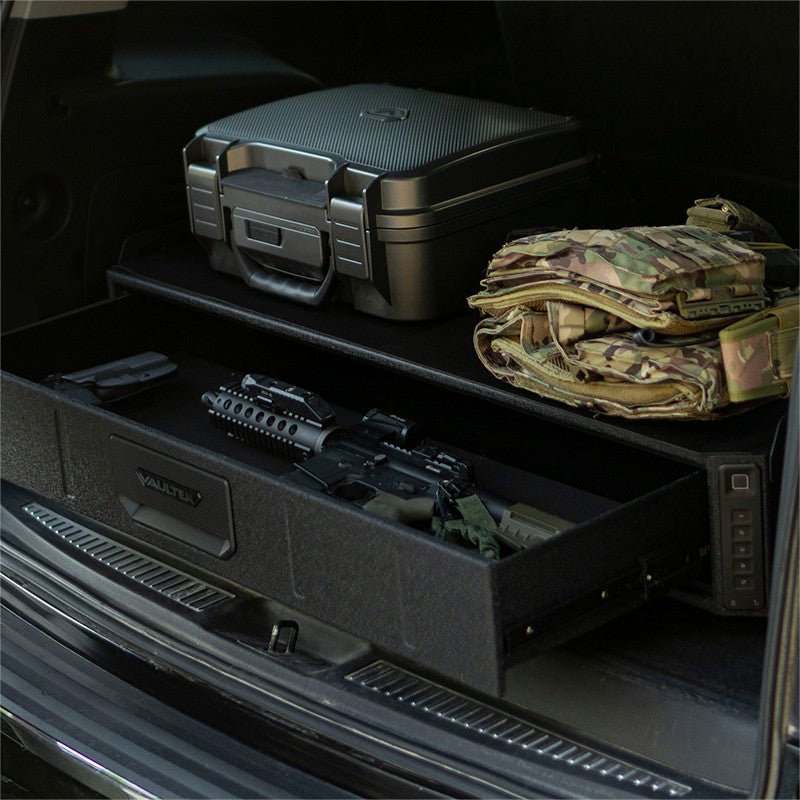 Vaultek SLV200i installed in an SUV cargo area with the drawer open showing an AR rifle and gear cases stored on top deck